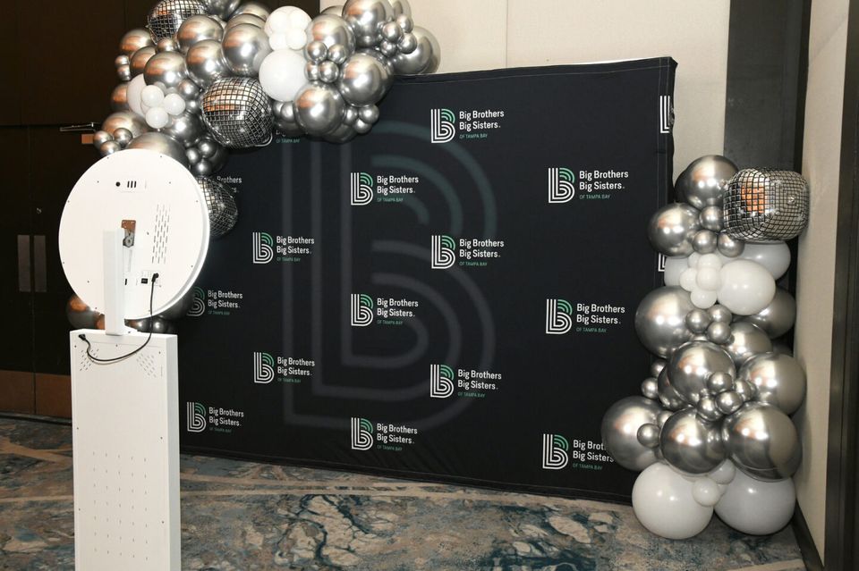 White selfie station with guest-supplied backdrop at a formal gala with balloon installation
