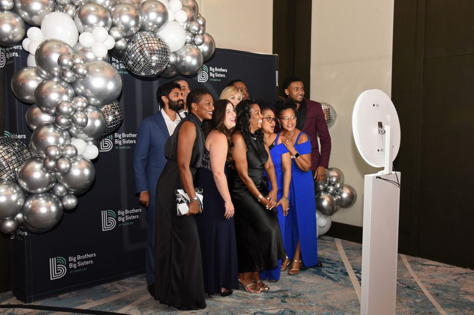 Group posing at the white selfie station with a guest-supplied backdrop