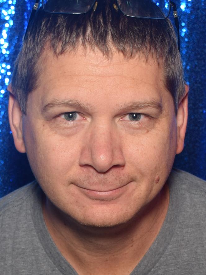 Josh in a gray tee in front of a blue sequin backdrop