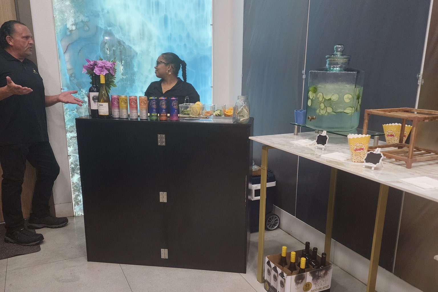 Black wooden folding mobile bar set up at an event with a bartender serving a guest
